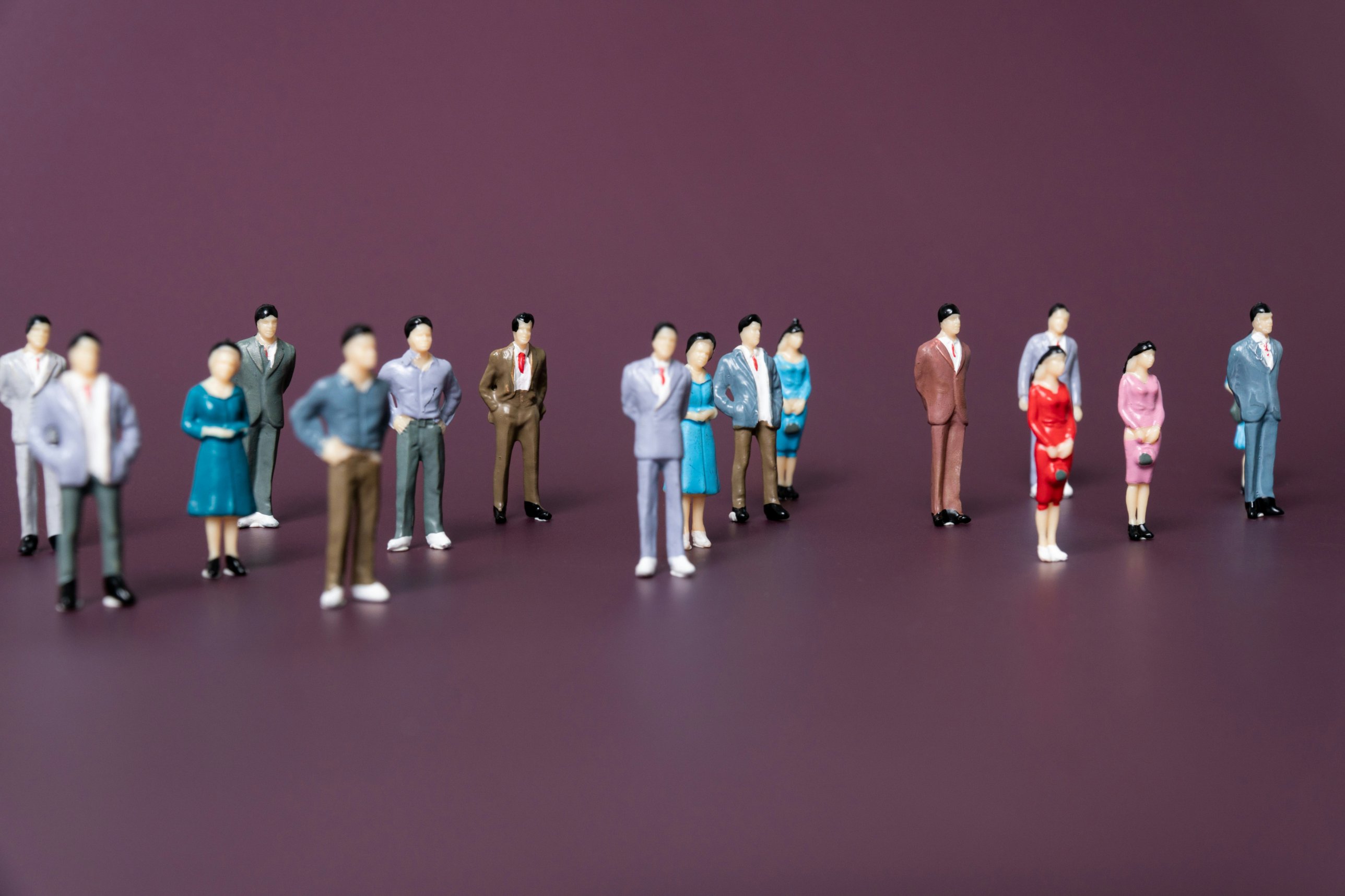 Miniature figurines of diverse professionals standing in groups representing how organisations group roles into job families